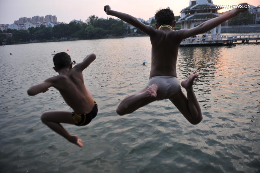 Two boys jump to the lake to cool himself off at the Huancheng Park in Hefei, capital of east China's Anhui Province, July 24, 2013. (Xinhua/Yang Xiaoyuan)