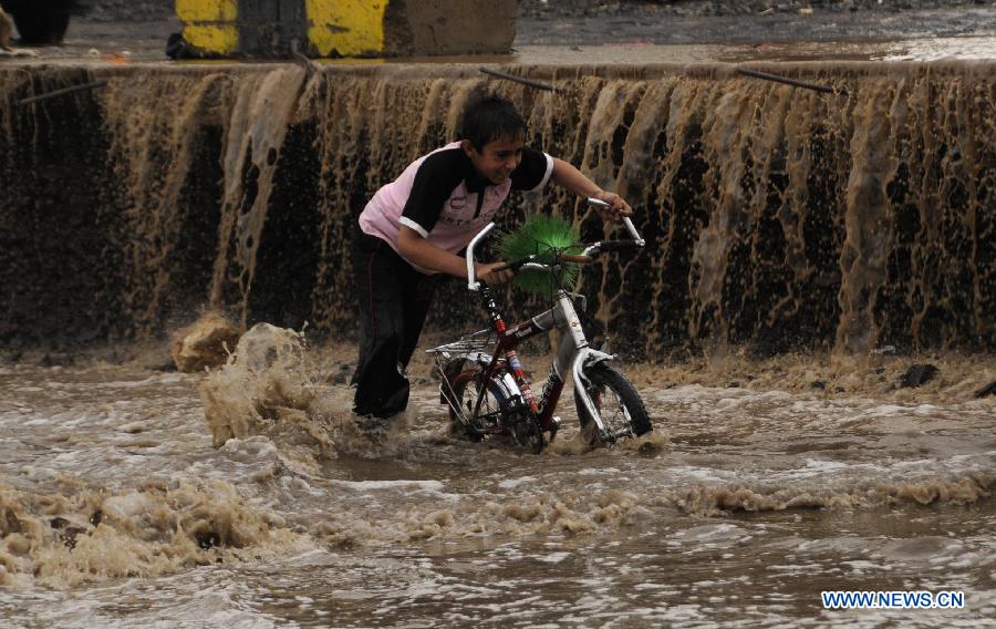 A Yemeni boy pushes his bike after heavy rain that caused flood on a street in Sanaa, Yemen, on July 27, 2013. The heavy rain in the Yemeni capital of Sanaa on Saturday caused flood in some districts. Some cars were trapped in the water and some roads were forced to be closed. (Xinhua/Mohammed Mohammed) 