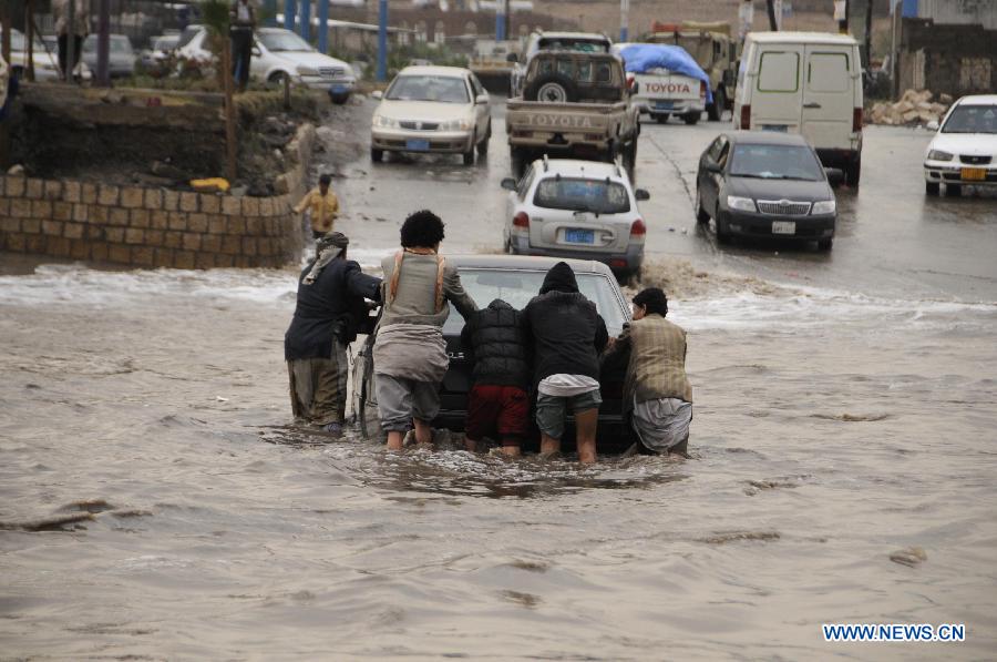 Several Yemenis pushes a car that was trapped after heavy rain that caused flood on a street in Sanaa, Yemen, on July 27, 2013. The heavy rain in the Yemeni capital of Sanaa on Saturday caused flood in some districts. Some cars were trapped in the water and some roads were forced to be closed. (Xinhua/Mohammed Mohammed) 