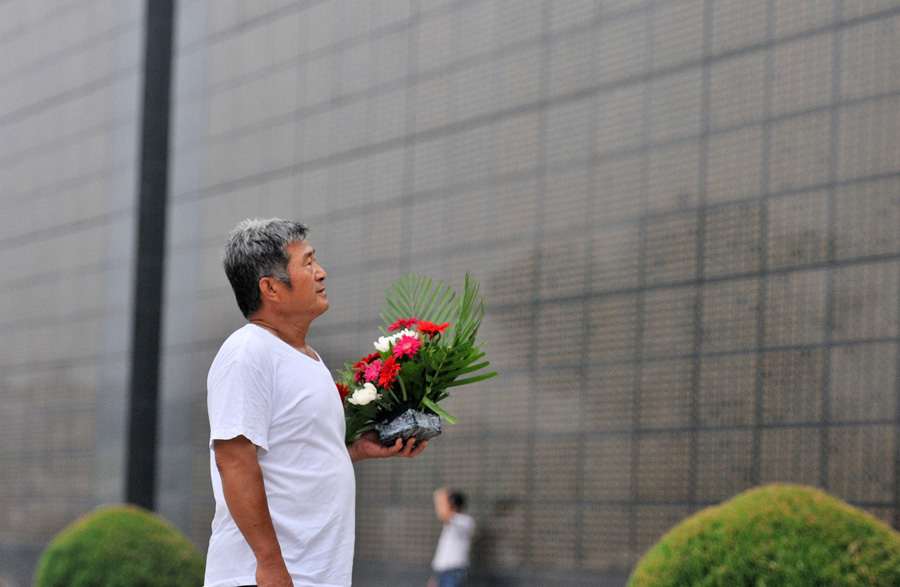 A man mourns for his relatives died in the 1976 Tangshan earthquake in front of the memorial wall in Tangshan, north China's Hebei Province, July 28, 2013. Local residents came to the memorial park on Sunday to commemorate the 37th anniversary of the Tangshan earthquake. (Photo/Xinhua)
