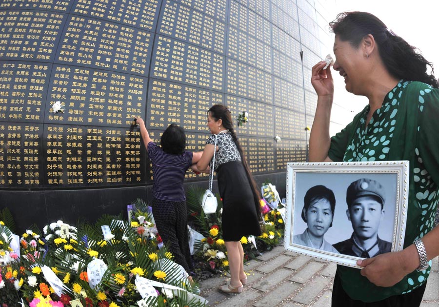 A woman holding a black and white photo mourns for her relatives died in the 1976 Tangshan earthquake in front of the memorial wall in Tangshan, north China's Hebei Province, July 28, 2013. Local residents came to the memorial park on Sunday to commemorate the 37th anniversary of the Tangshan earthquake. (Photo/Xinhua)