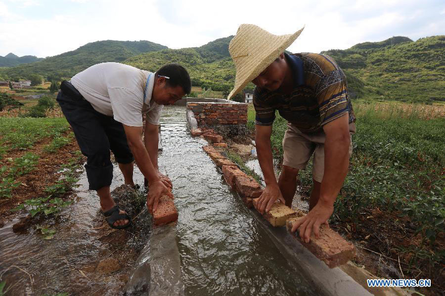 Villagers repair a water channel at Pingdi Village in Loudi City, central China's Hunan Province, July 27, 2013. A drought that has already lasted several weeks is continuing to linger in Hunan, leaving 533,000 people short of drinking water. (Xinhua/Guo Guoquan)