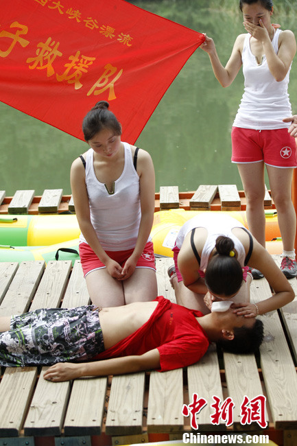 A woman demonstrates an emergency procedure consisting of external cardiac massage and artificial respiration on a man in Yuxi Grand Canyon, central China’s Henan province on July 25, 2013.(Photo by Wang Zhongju/ Chinanews.com)