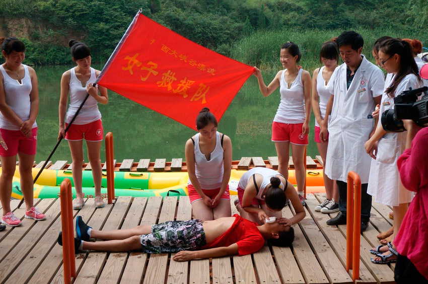 A woman demonstrates an emergency procedure consisting of external cardiac massage and artificial respiration on a man in Yuxi Grand Canyon, central China’s Henan province on July 25, 2013. (Photo/ people.com.cn)
