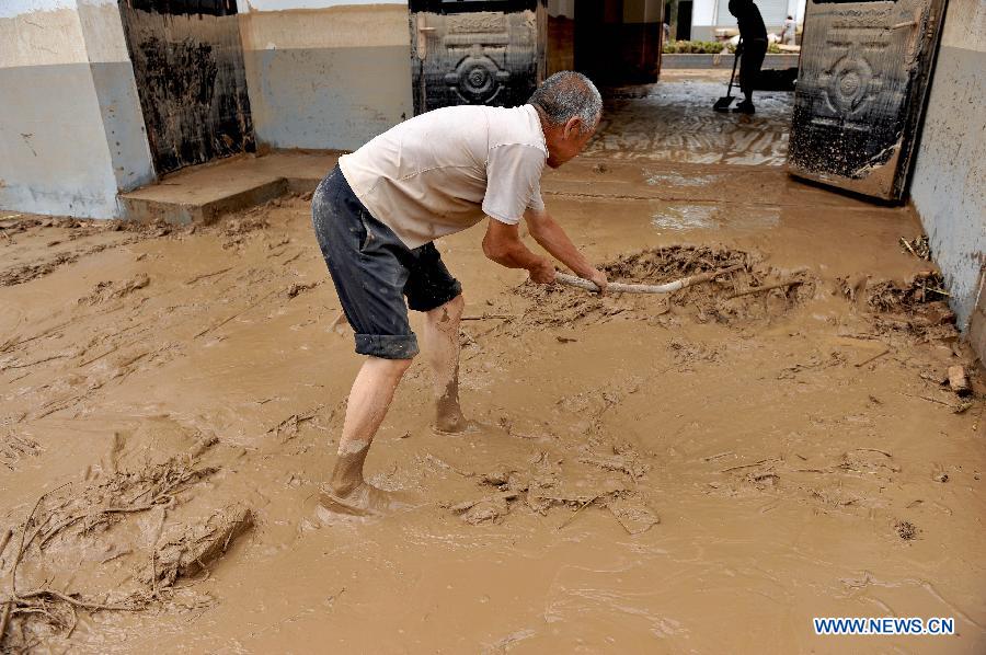 An elder cleans silt in front of his house in Yunyan Town, Yichuan County of northwest China's Shaanxi Province, July 28, 2013. Lasting Heavy rainfall in July has affected 13 counties in Yan'an City. (Xinhua/Qi Xiaojun) 