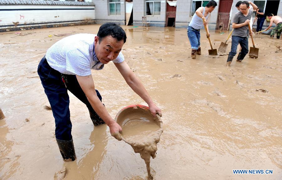 People clean silt in a yard in Yunyan Town, Yichuan County of northwest China's Shaanxi Province, July 28, 2013. Lasting Heavy rainfall in July has affected 13 counties in Yan'an City. (Xinhua/Qi Xiaojun) 