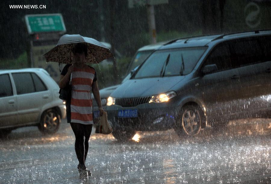 A passenger walks in torrential rain on the Yuhan Road in Jinan, capital of east China's Shandong Province, July 29, 2013. A sudden downpour hit the city on Monday afternoon. (Xinhua/Zhu Zheng)