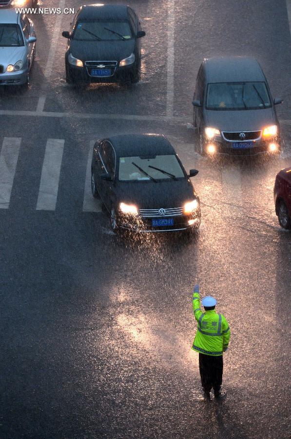 A traffic policeman directs the traffic in torrential rain in a street in Jinan, capital of east China's Shandong Province, July 29, 2013. A sudden downpour hit the city on Monday afternoon. (Xinhua/Guo Xulei)