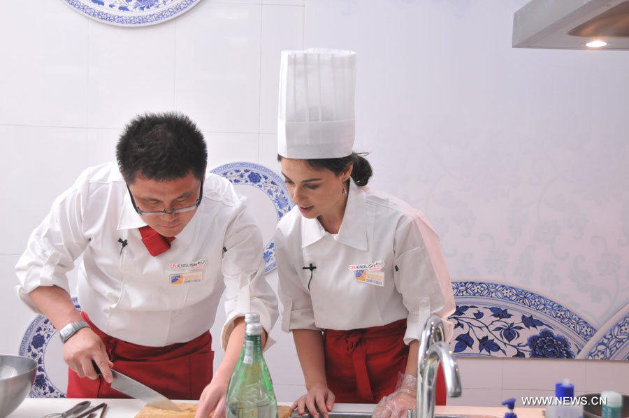 Judge and World Association of Chinese Cuisine chef Tang Xipeng shows French contestant Ana Perez how to make fine slicing during "Chopsticks and Beyond" Cantonese Cuisine Competition on June 27, 2013. "Chopsticks and Beyond" is a Chinese cuisine challenge launched by CRIENGLISH.com to provide a platform for foreign food enthusiasts to show off their Chinese cooking skills and explore creative dishes with exotic flavor. It features China's four great traditions: Sichuan Cuisine, Cantonese Cuisine, Shandong Cuisine and Huaiyang Cuisine. (Xinhuanet/Yang Yi)