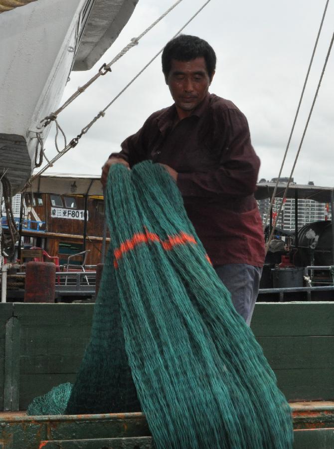 A fisherman prepares fishing nets at the port of Sanya, south China's Hainan Province, July 29, 2013. As the two-and-half-month summer fishing moratorium is going to end on Aug. 1, fishermen prepared to resume fishing in Hainan. (Xinhua/Wang Junfeng)