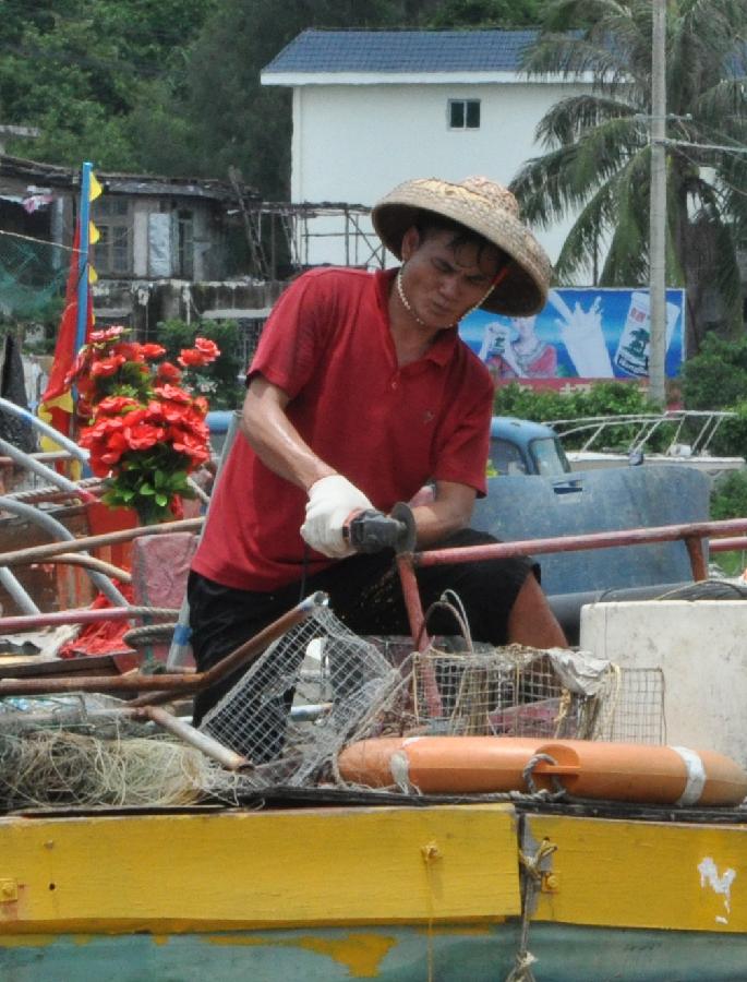 A fisherman fixes a boat at the port of Sanya, south China's Hainan Province, July 29, 2013. As the two-and-half-month summer fishing moratorium is going to end on Aug. 1, fishermen prepared to resume fishing in Hainan. (Xinhua/Wang Junfeng)