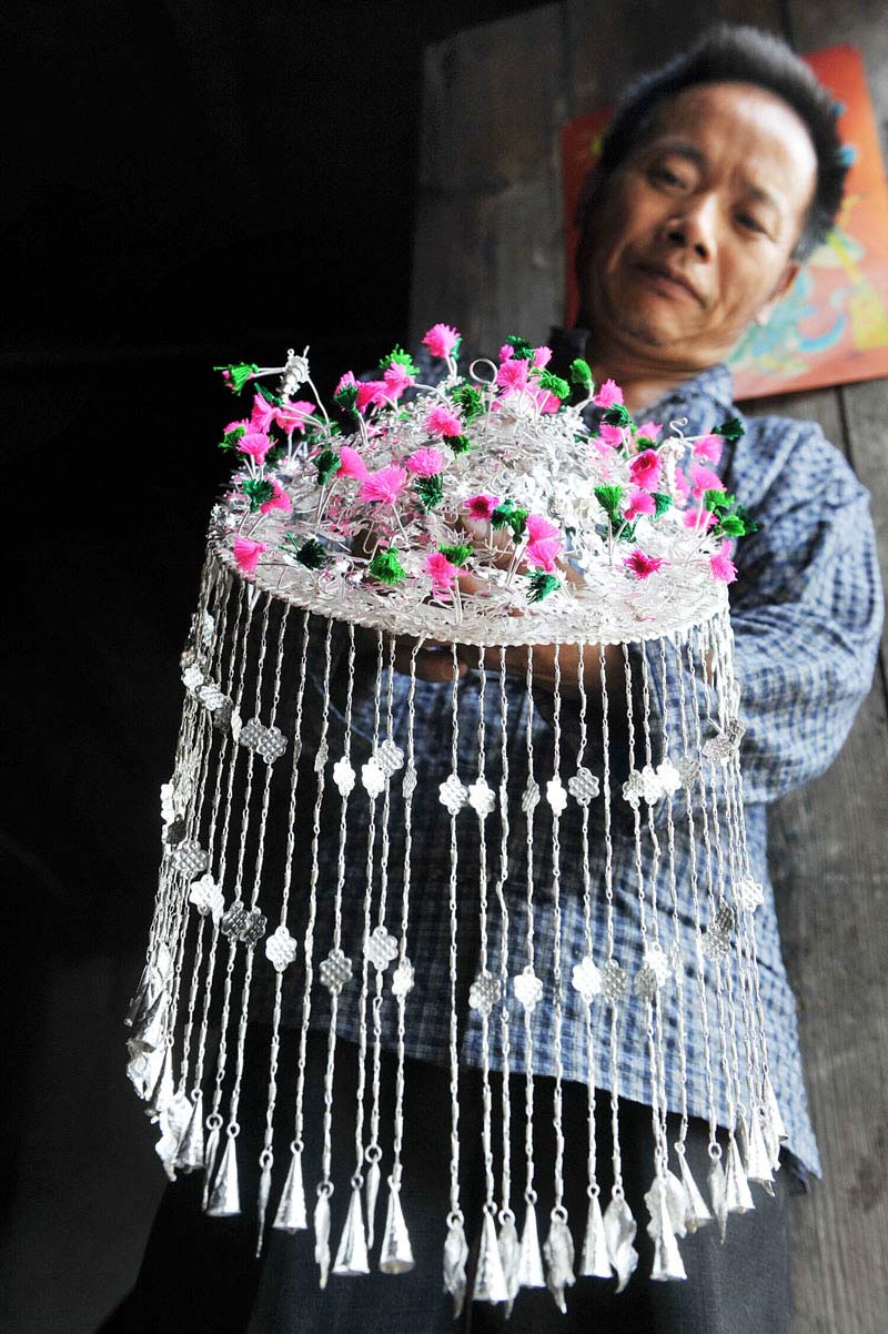 Ma Maoting shows a silver headpiece he handmade in a flashback to ancient times on July 24, 2013. Sixty-year-old Ma is from Huangmaoping village of Xiangxi Tujia and Miao autonomous prefecture in Hunan province. The village has been famous for handmade silver jewelry from ancient times and Ma is the 5th-generation of his family to make a living from their handicraft. It takes nearly 30 steps to make a piece of silver jewelry of the Miao ethnic group. Ma Maoting was honored as heir to Miao ethnic group silver jewelry forging skill in national intangible cultural heritage status in June, 2009. (Photo/Xinhua)