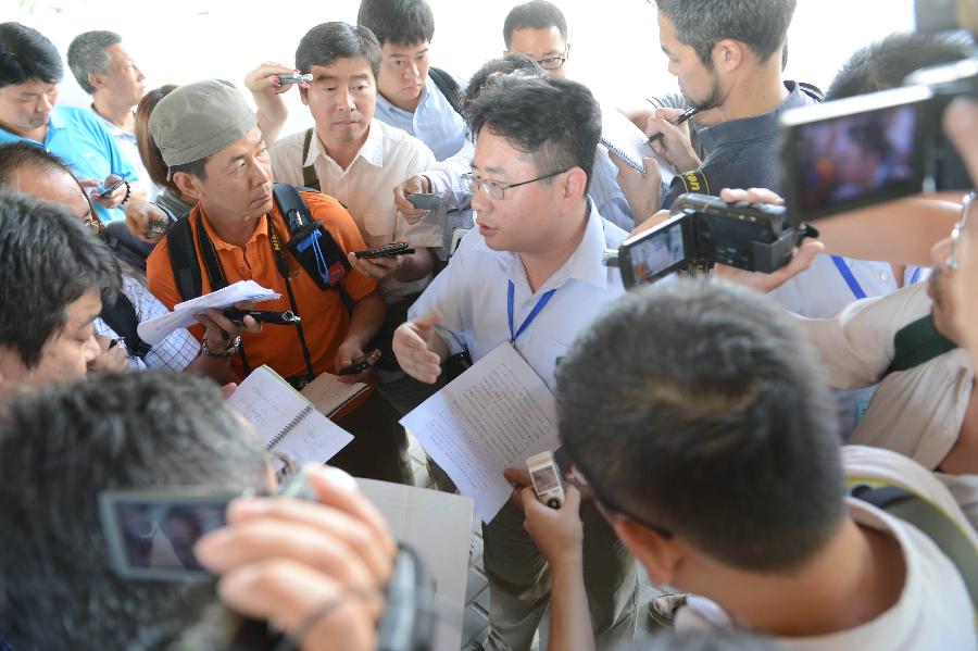 A Japanese journalist (C) introduces the trial process to media staff members outside the Shijiazhuang Intermediate People's Court after the trial in Shijiazhuang, north China's Hebei Province, July 30, 2013. The court on Tuesday opened a trial for a man who allegedly added poison to frozen dumplings that sickened four Chinese and nine Japanese citizens in 2008. (Xinhua/Wang Min) 