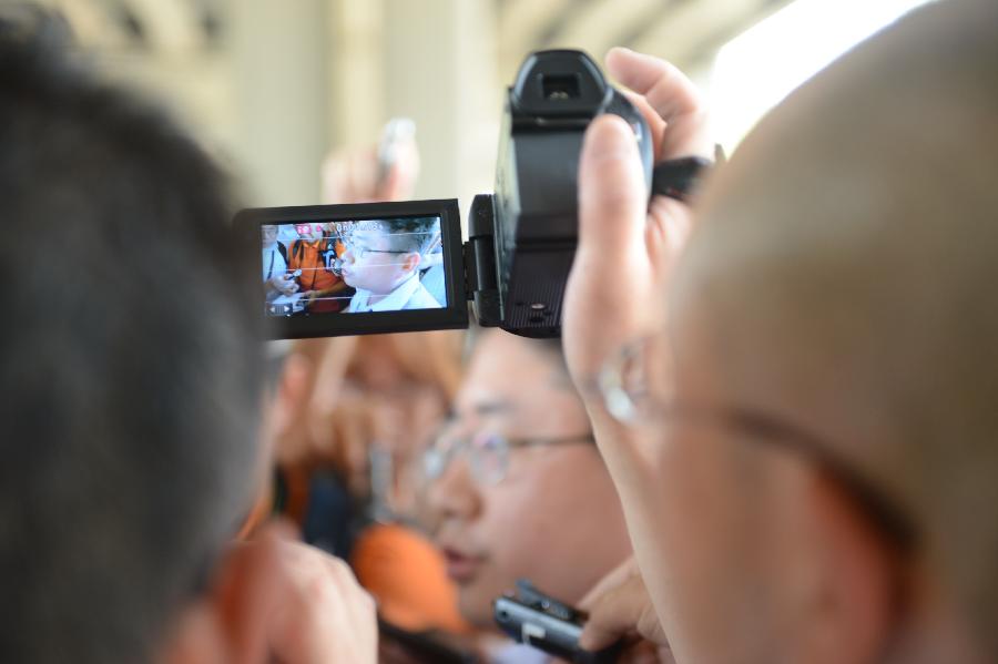 A Japanese journalist (the one in the vidicon) introduces the trial process to media staff members outside the Shijiazhuang Intermediate People's Court after the trial in Shijiazhuang, north China's Hebei Province, July 30, 2013. The court on Tuesday opened a trial for a man who allegedly added poison to frozen dumplings that sickened four Chinese and nine Japanese citizens in 2008. (Xinhua/Wang Min) 