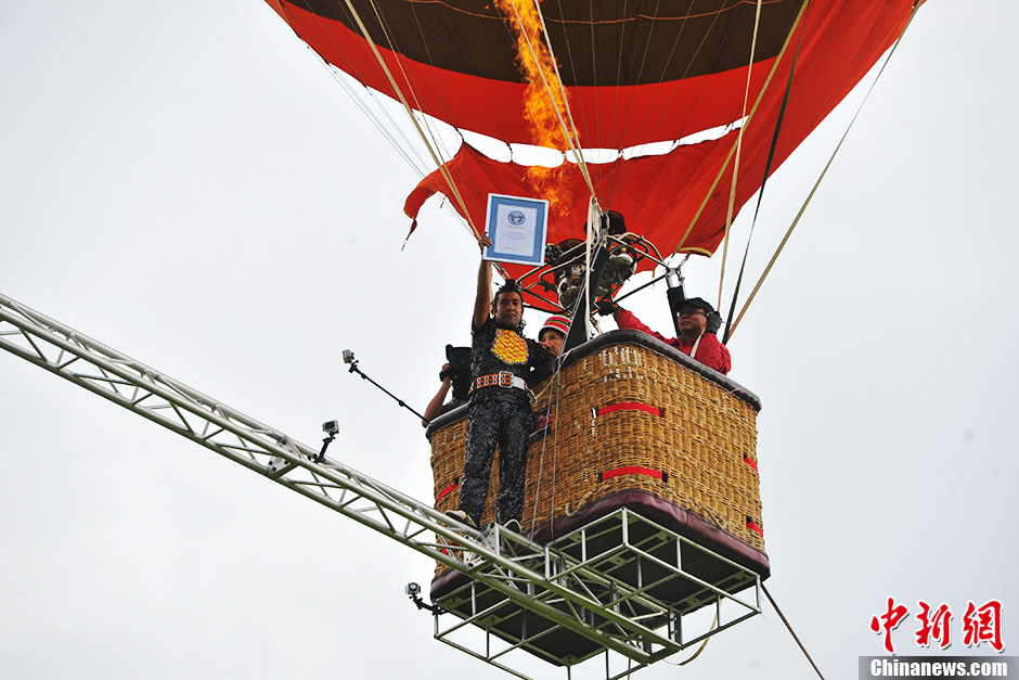 Askar, 40, from Xinjiang, has set a new world record after walking on a tightrope between two moving balloons at high altitude in Shilin, southwest China’s Yunan province on July 30, 2013. He has set World Guinness records for five times. With the help of a steel beam with a diameter of 50 millimeters Askar covered a distance of 18 meters in the air on the rope. (Photo by Ren Dong/ Chinanews.com)