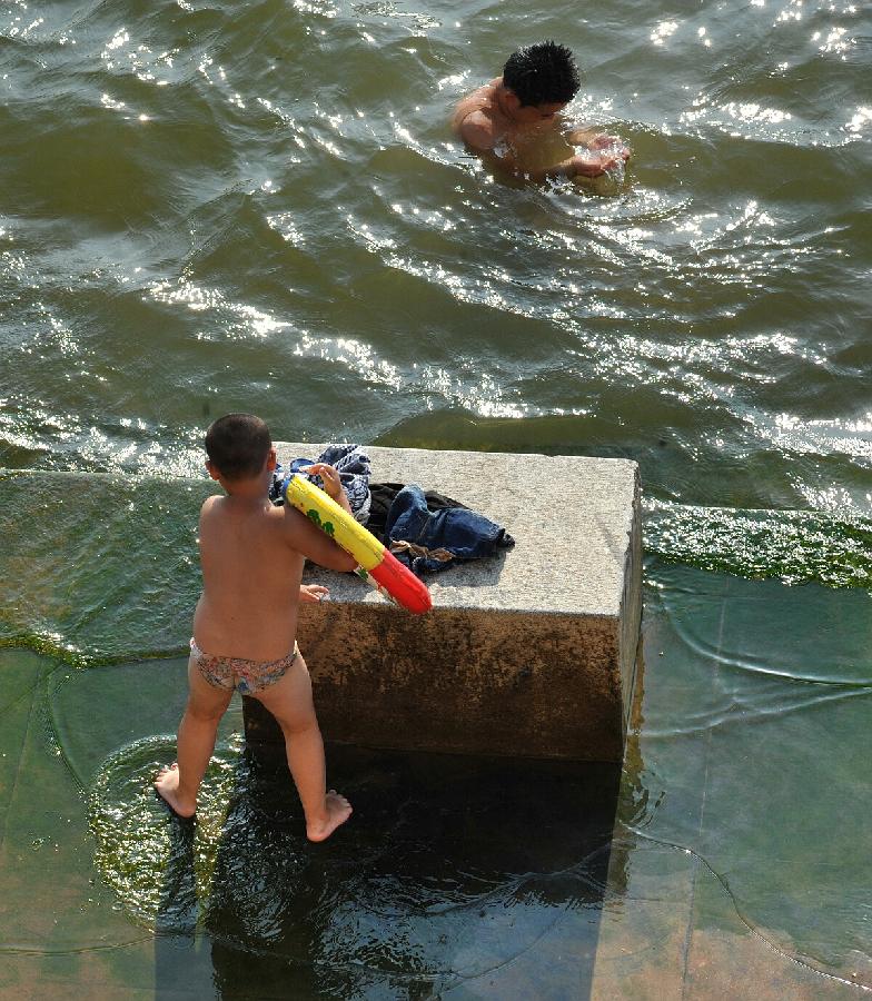 Citizens play along the Xiangjiang River in the burning sun in Changsha, capital of central China's Hunan Province, July 30, 2013. High temperatures sustained in the past month in Changsha and will continue in the coming 4 days. (Xinhua/Long Hongtao)