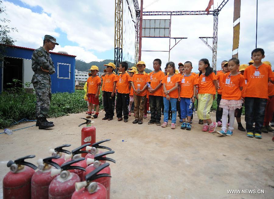 An instructor introduces fire control and protection knowledge to children at the provincial youth fire control and protection education base in Kunming, capital of southwest China's Yunnan Province, July 30, 2013. More than 80 migrant children in Kunming participated in a summer camp, which lasts from July 29 to Aug. 1, where they can learn knowledge related with transportation safety, fire control and earthquake protection at the base. (Xinhua/Qin Lang)