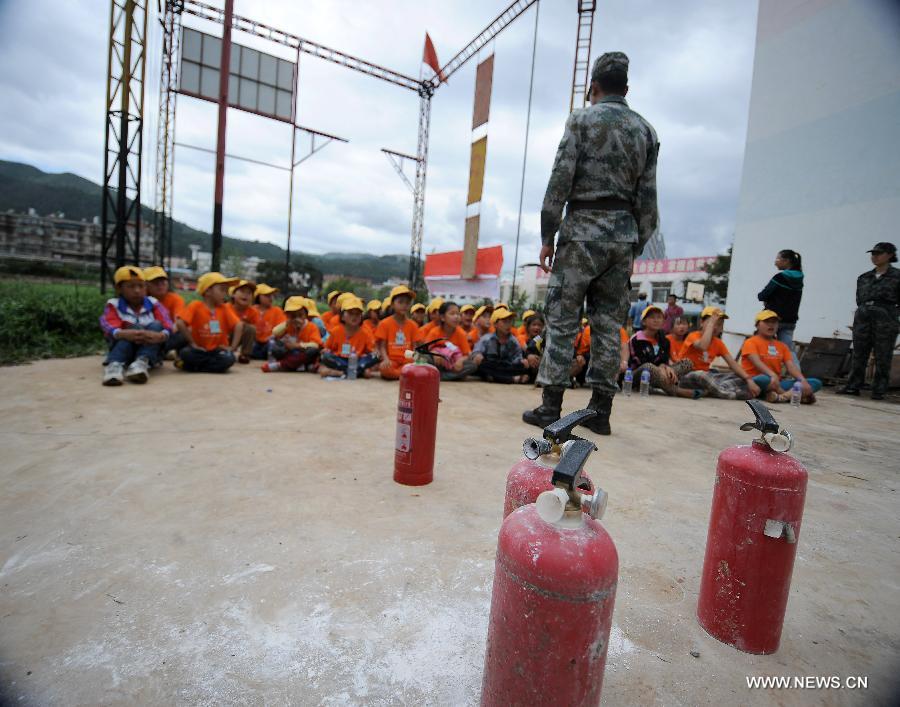 An instructor introduces fire control and protection knowledge to children at the provincial youth fire control and protection education base in Kunming, capital of southwest China's Yunnan Province, July 30, 2013. More than 80 migrant children in Kunming participated in a summer camp, which lasts from July 29 to Aug. 1, where they can learn knowledge related with transportation safety, fire control and earthquake protection at the base. (Xinhua/Qin Lang)