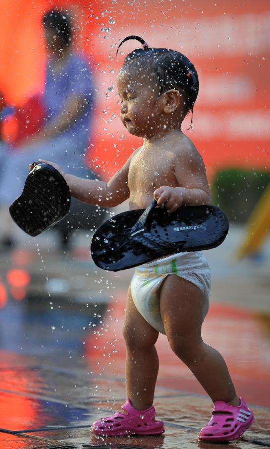 A little girl plays with water near a fountain in Sanlitun of Beijing, capital of China, July 30, 2013. The temperature in most parts of Beijing climbed as high as 34 degrees Celsius Tuesday afternoon. The China Meteorological Administration has launched a level two emergency response to heat for the first time this year on Tuesday, covering regions including east China's Anhui, Jiangsu, Zhejiang and Jiangxi,central China's Hunan and Hubei, south China's Fujian, and Shanghai and Chongqing municipalities. (Xinhua/Chen Yehua)