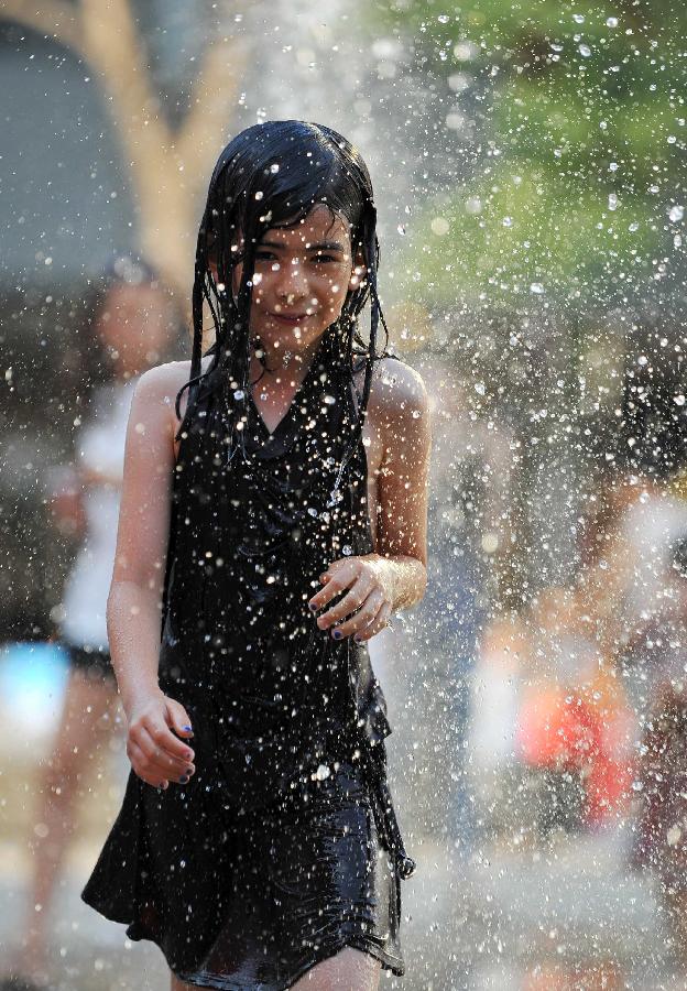 A little girl plays with water near a fountain in Sanlitun of Beijing, capital of China, July 30, 2013. The temperature in most parts of Beijing climbed as high as 34 degrees Celsius Tuesday afternoon. The China Meteorological Administration has launched a level two emergency response to heat for the first time this year on Tuesday, covering regions including east China's Anhui, Jiangsu, Zhejiang and Jiangxi,central China's Hunan and Hubei, south China's Fujian, and Shanghai and Chongqing municipalities. (Xinhua/Chen Yehua)