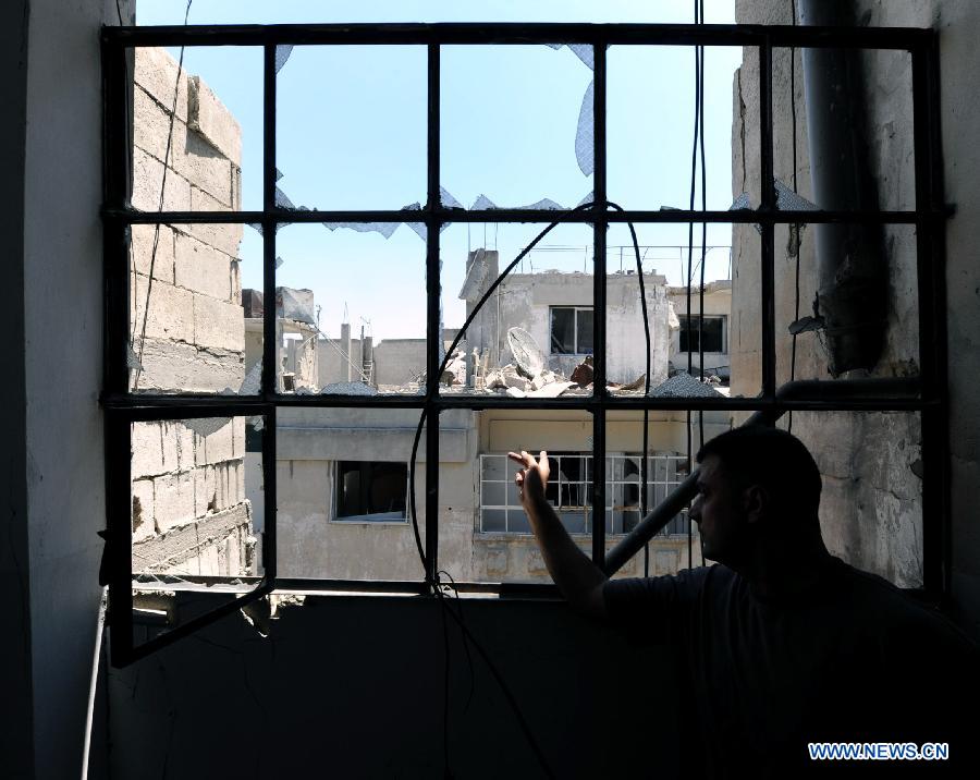 A soldier of the Syrian army talks in front of a window in al-Khalidieh district in central Homs province, Syria, July 30, 2013. The Syrian army announced Monday that its troops successfully regained full control over the strategic al-Khalidieh district in central Homs province after a series of precise operations there, according to the state-TV. (Xinhua/Zhang Naijie)