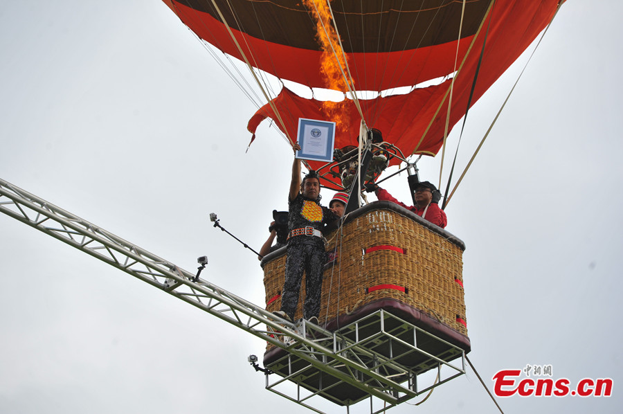 Chinese tightrope walker Aisikaier Wubulikaisimu sets the new Guinness World Record by successfully walking across a steel beam lifted by two fire balloons which is 18 meters long and only 5 centimeters wide in 38.35 seconds in Naigu Stone Forest Scenic Spot, Yunnan province on July 30, 2013. (CNS/ Ren Dong)