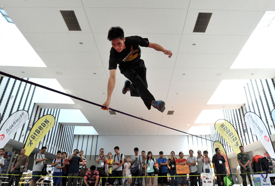 An outdoor enthusiast performs slacklining on July 24. On the same day, Asia Outdoor Trades Show was held in International Expo Center of Nanjing. Slacklining originated from wirewalking, but it is more difficult. (Xinhua)