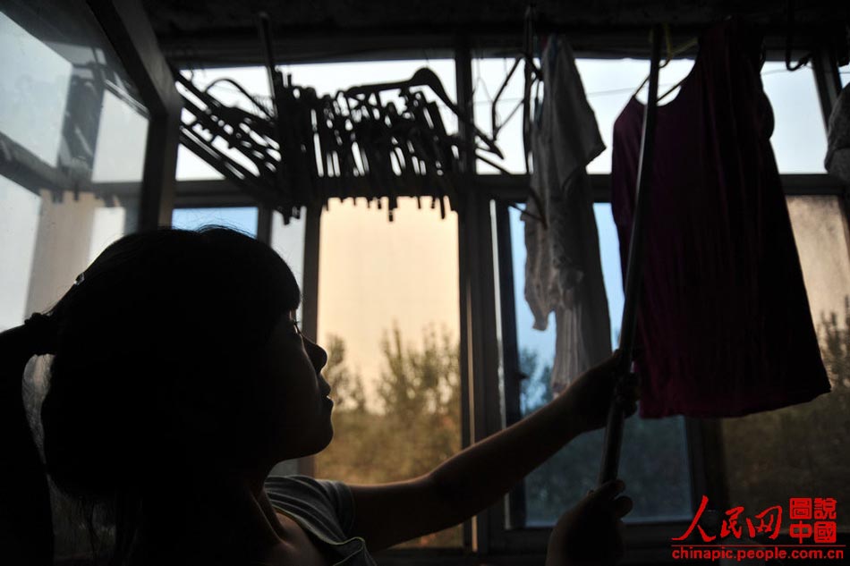 Gao hangs up the washed clothes at home in Tianjing on July 12, 2013. She has learned to take care of the whole family since she was five.