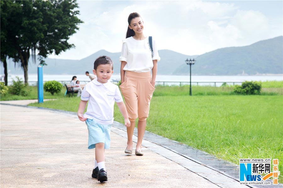 Chinese actress Cecilia Cheung poses for photos of an advertisement with a cute boy. (Photo/Xinhua)