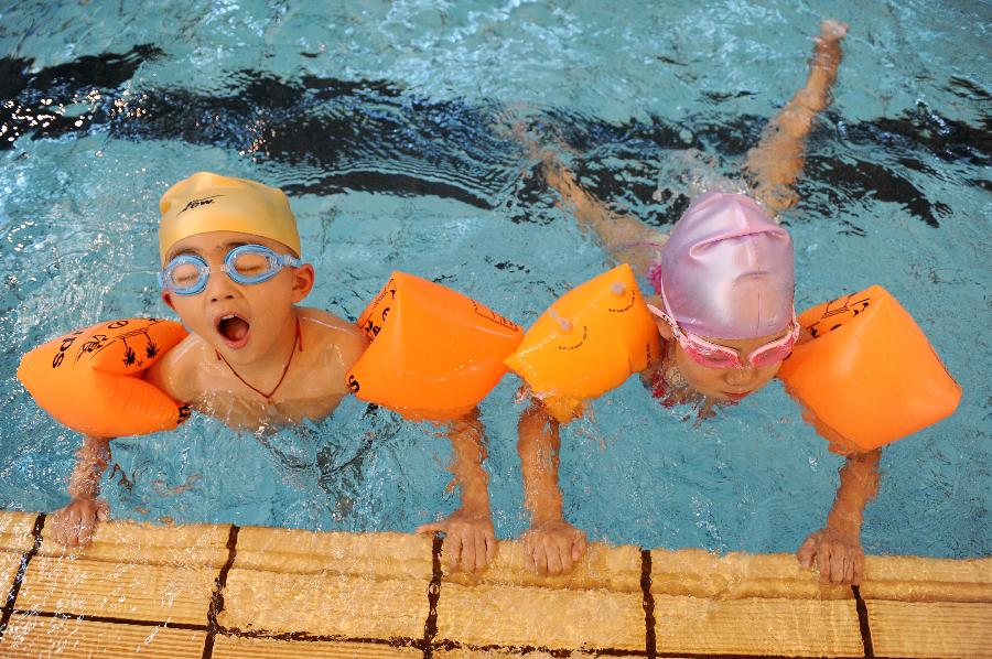 Children learn swimming at an indoor pool in Hangzhou, capital of east China's Zhejiang Province, July 31, 2013. Hangzhou has experienced six days of temperature over 40 degrees Celsius since July 24. Indoor activities like ice skating and swimming has been popular among local citizens to relieve the intense heat. (Xinhua/Ju Huanzong)
