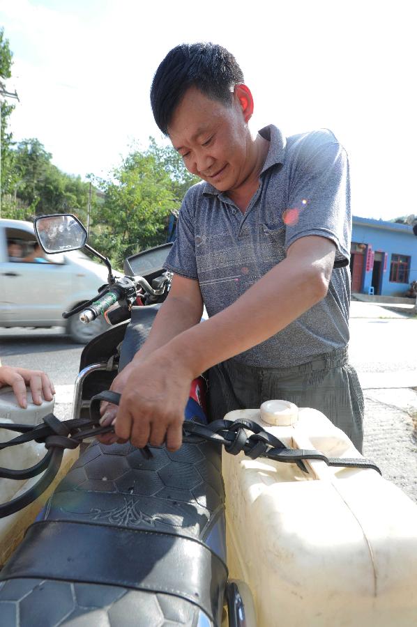 A man carries water by motercycle in the Jinba Village of Jinsha County, southwest China's Guizhou Province, July 31, 2013. Lingering droughts in Guizhou have affected more than 12 million people. Over 2 million people lack adequate supplies of drinking water, and a total of 847,300 hectares of farmland is damaged by the drought. (Xinhua/Yang Ying)