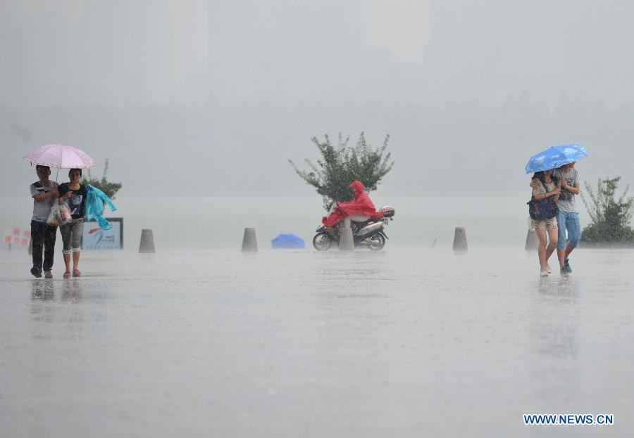Citizens walk in the rain in Nanjing, capital of east China's Jiangsu Province, July 31, 2013. An artificial precipitation brought coolness to citizens in Nanjing. (Xinhua/Lang Congliu)