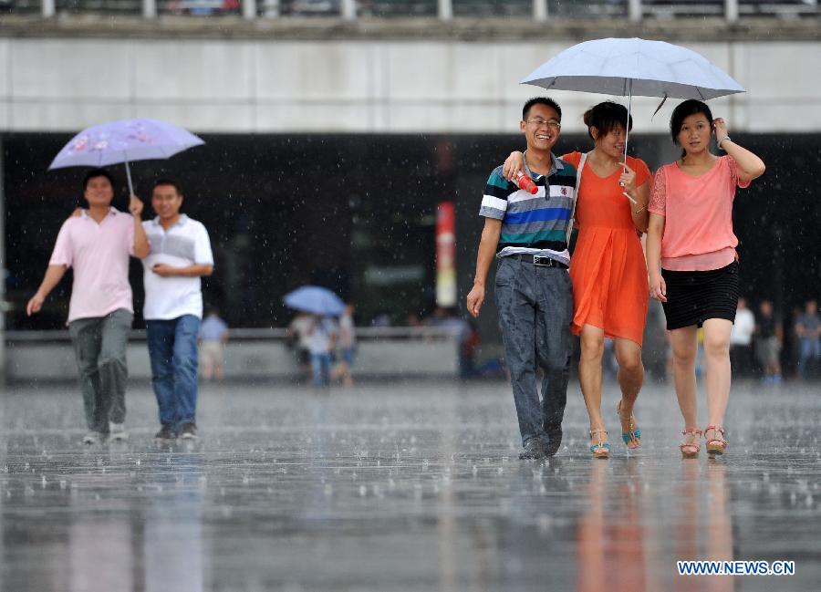 Citizens walk in the rain in Nanjing, capital of east China's Jiangsu Province, July 31, 2013. An artificial precipitation brought coolness to citizens in Nanjing. (Xinhua/Lang Congliu)