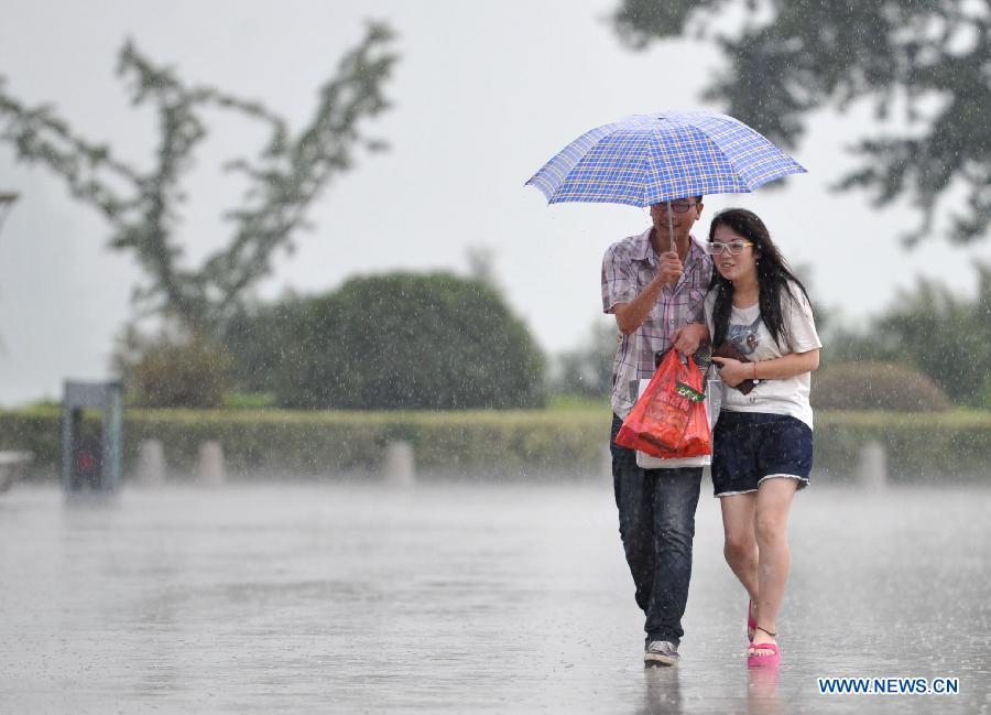 Citizens walk in the rain in Nanjing, capital of east China's Jiangsu Province, July 31, 2013. An artificial precipitation brought coolness to citizens in Nanjing. (Xinhua/Lang Congliu)