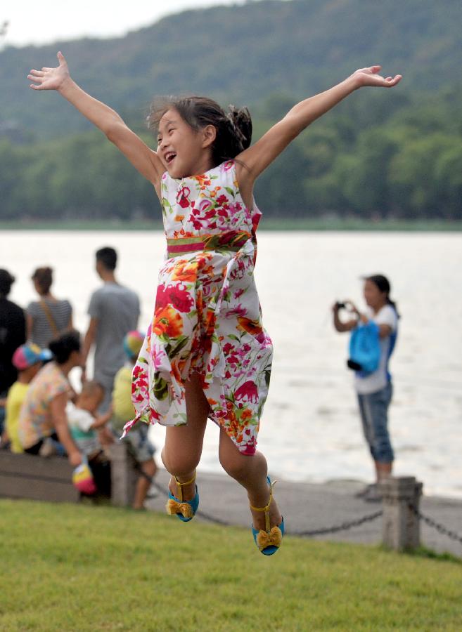 A little girl enjoy herself on the Baidi Causeway at the West Lake in Hangzhou, capital of east China's Zhejiang Province, July 31, 2013. A thunder shower on Wednesday brought cool to Hangzhou, a city that has experienced six days of temperature over 40 degrees Celsius since July 24. (Xinhua/Wang Dingchang)