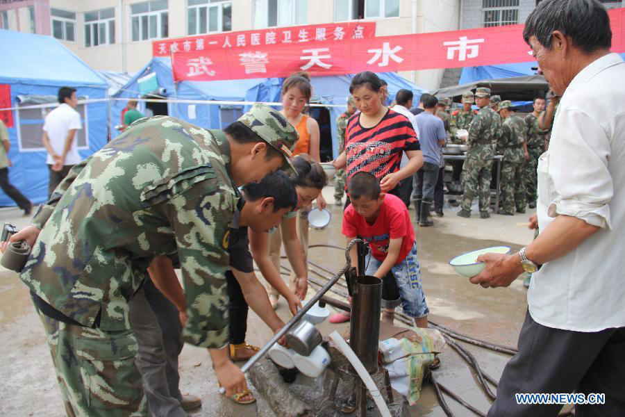 Soldiers help people get water in the flooded Niangniangba Town, Qinzhou District of Tianshui City, northwest China's Gansu Province, July 31, 2013. More than 20 people were dead or missing and about 1.22 million people were affected by the landslides and floods caused by strong rainfall in Tianshui in recent days. (Xinhua/Bai Liping)