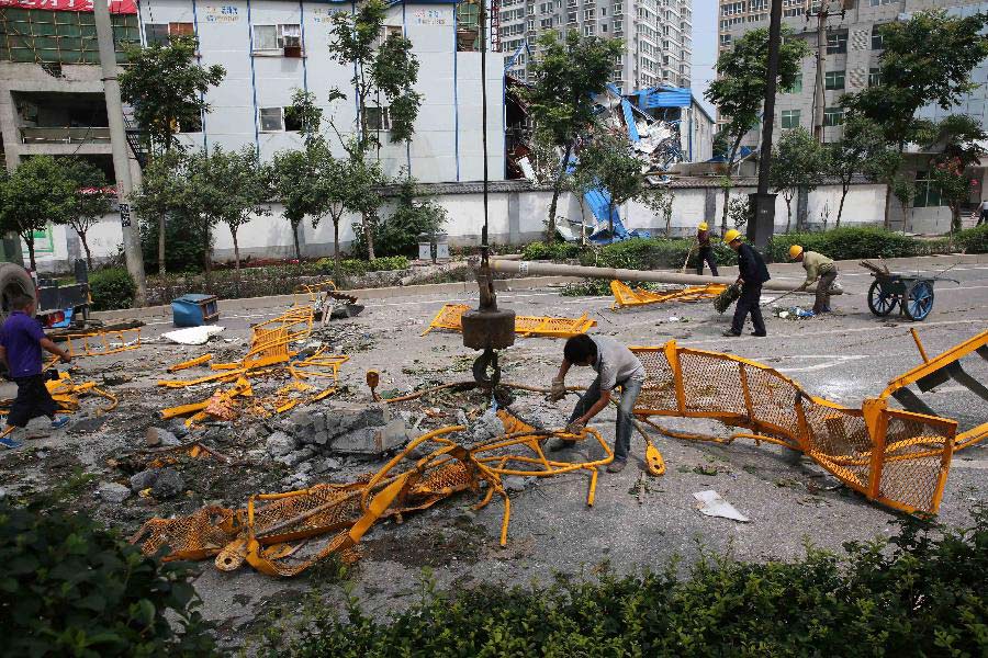 Workers clean the accident scene where the fallen tower crane damaged the prefab houses at a construction site in Xi'an, capital of northwest China's Shaanxi Province, Aug. 1, 2013. Due to sudden thundershower and strong wind, a tower crane at a construction site in Xi'an on early Thursday fell to the prefab houses where lived construction workers, killing four people and hurting four others. (Xinhua/Hou Zhi) 