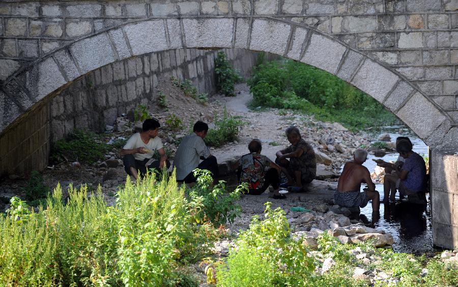 Villagers sit under a bridge where plenty of river water used to flow through in Dongshan Village of Yuyao, east China's Zhejiang Province, Aug. 13, 2013. High temperatures and scarce rainfall which have lasted over 40 days resulted in severe damage of agriculture and shortage of drinking water for over 417,000 people in Zhejiang. The heat is expected to continue in the following days, according to the local meteorological authority. (Xinhua/Wang Dingchang) 