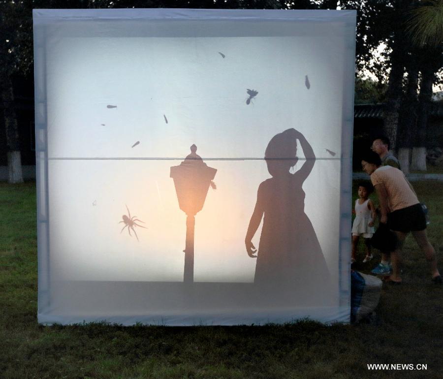 A girl is silhouetted behind a light device on the lawn at the "2013 Switch on Beijing International Light Festival" in the Ditan Park, Beijing, China, Aug. 17, 2013. The art event is held here on Aug. 16 -18. (Xinhua)
