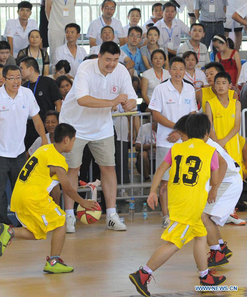 Former NBA player Yao Ming (2nd L, back) cheers for little players during a basketball match of the eastern division of the Yao Foundation Hope Primary School Basketball Season, in Lu'an City, east China's Anhui Province, Aug. 15, 2013. The basketball season was held to let the children in impoverished regions to enjoy the happiness of sports and grow up healthily. (Xinhua/Chen Li)