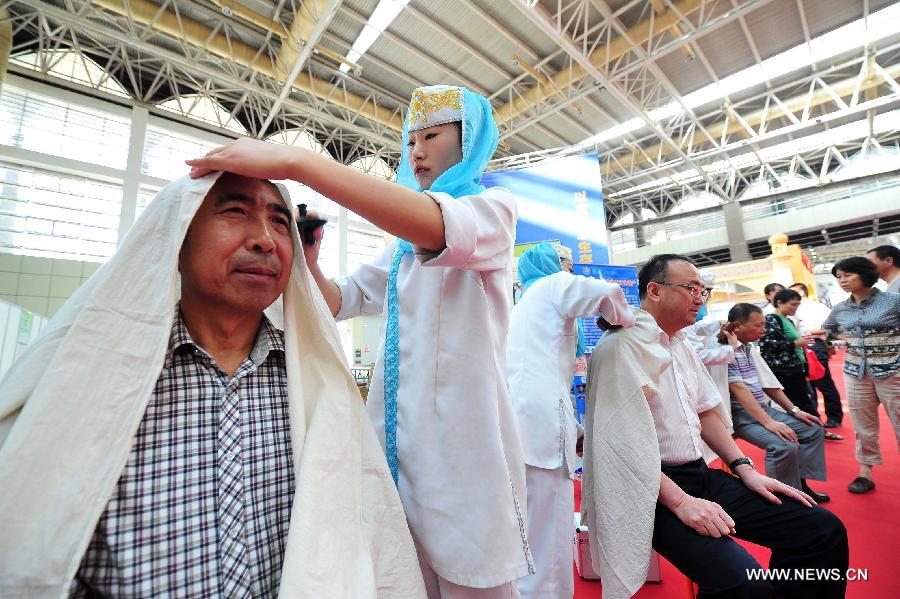 Visitors experience traditional therapy of the Hui ethnic group at an expo of medicine and pharmacy of ethnic minorities, in Yinchuan, capital of northwest China's Ningxia Hui Autonomous Region, Aug. 31, 2013. The three-day expo kicked off Friday here. (Xinhua/Peng Zhaozhi)