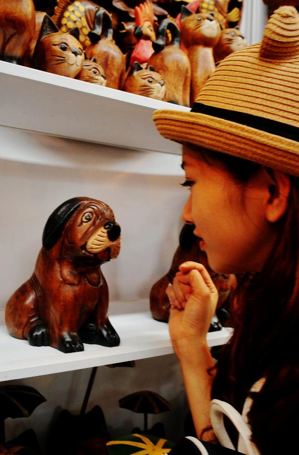 A visitor views a woodcarved dog from Vietnam at the 10th China-ASEAN Expo in Nanning, capital of south China's Guangxi Zhuang Autonomous Region, Sept. 4, 2013. Opened in Nanning on Tuesday, the expo attracted more than 2,300 companies from China and the Association of Southeast Asian Nations (ASEAN). (Xinhua/Zhang Ailin) 