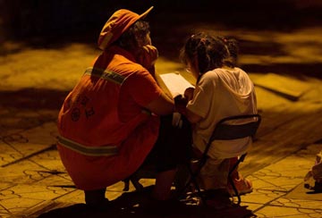 Maternal love under streetlight: Mother accompanies daughter to study beside road 