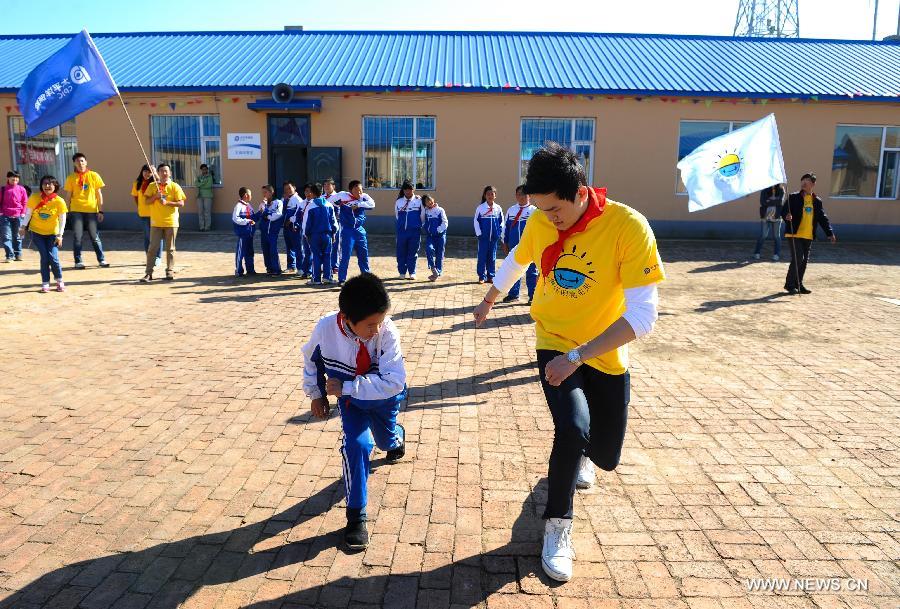 China's Olympic swimming champion Sun Yang (R) exercises with a boy in a primary school in Dehui, northeast China's Jilin Province, China, Sept. 26, 2013. Sun Yang showed up as a volunteer teacher in the school Thursday, bringing professtional physical education classses to over one hundred children of the school. (Xinhua/Xu Chang)
