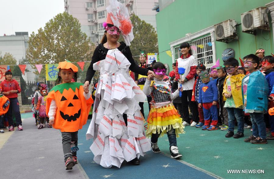 A teacher and children show costumes made with recycled materials to greet the Halloween in a kindergarten in Handan City, north China's Hebei Province, Oct. 31. The World Thrift Day fell on Thursday, a day before the All-Saint's Day this year. (Xinhua/Hao Qunying) 