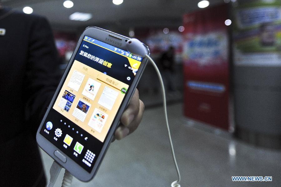 A staff member presents a Samsung 4G mobile phone at Xizhimen business hall of China Mobile in Beijing, Nov. 6, 2013. The Beijing company of China Mobile officially released its 4G mobile phones on Wednesday. (Xinhua/Wang Jingsheng) 