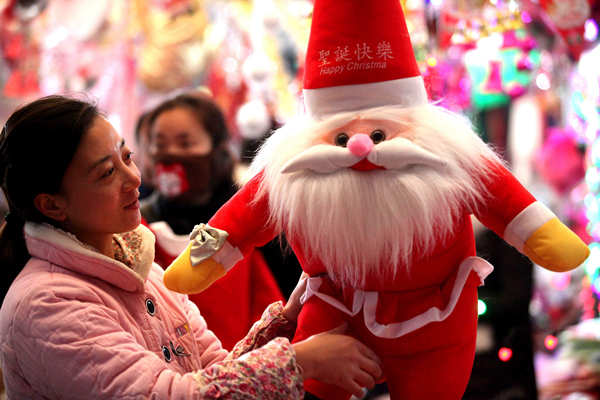 A customer chooses a doll for Christmas at a market in Bozhou, Anhui province. (China Daily/Liu Qinli)
