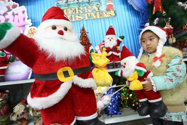 A girl takes stock of Santa at a mall in Xuchang, Henan province. (China Daily/Geng Guoqing)