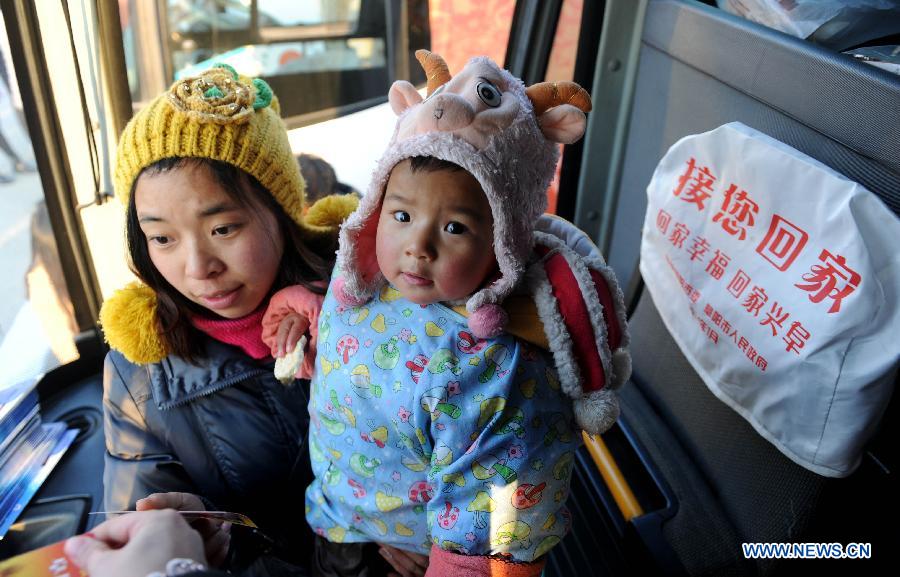 A passenger with child gets on a free bus at Fuyang railway station, east China's Anhui Province, Jan. 22, 2014. "Take You Home", a free bus service provided by the local government, was launched today at Fuyang railway station. The program will be serving from Jan. 22 to 28 for passengers going home for the Spring Festival. (Xinhua/Liu Junxi)