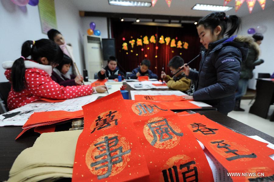Pan Xiaoyan (1st R), an 8-year old girl, and other children write Chinese couplets to greet the upcoming Spring Festival, in Hangzhou City, capital of east China's Zhejiang Province, Jan. 22, 2014. Chinese have the tradition to fix the couplet, which are red scrolls with rhyming phrases, on their doors during the Spring Festival, hoping it can bring in good luck. The Spring Festival falls on Jan. 31 this year. (Xinhua/Ju Huanzong) 